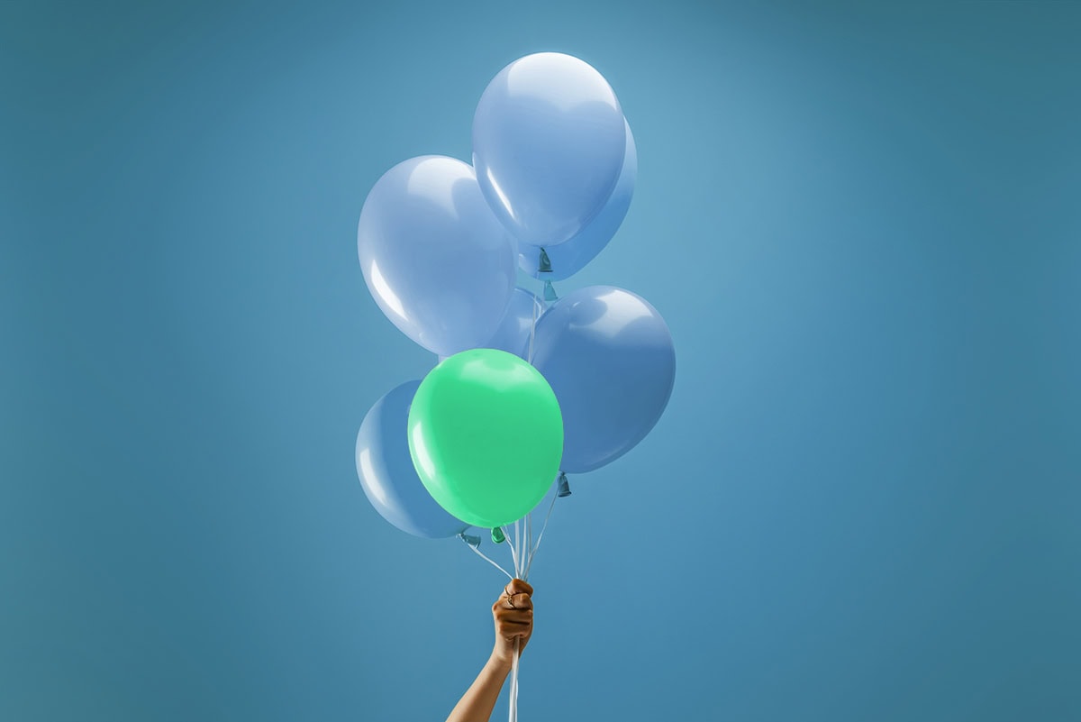 Luftballons Luftballons werden von einer Hand gehalten. Einer der Ballons ist grün.